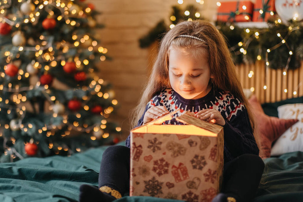 Excited girl opens gift box from Santa Claus, happy childhood, holiday celebration, Christmas miracle - Photo, Image
