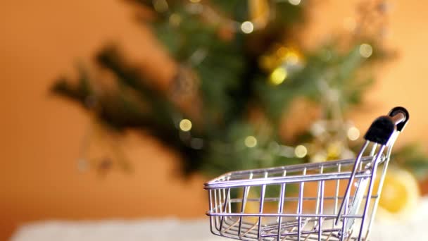 Close up mano mettere i regali in miniatura carrello della spesa. Acquisto vacanze di Natale. Lista dei desideri. Prepararsi per le vacanze - Filmati, video