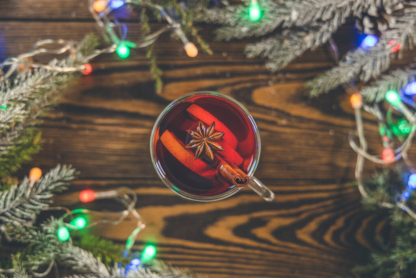 Kerst warme glühwein in een glas met specerijen en citrusvruchten. Glühwein met kaneel, anijs en sinaasappel. Bovenaanzicht en kopieerruimte. - Foto, afbeelding