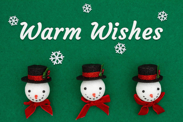Warme wensen begroeten met kerst sneeuwpoppen met top hoeden op groen vilt - Foto, afbeelding