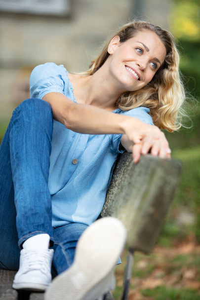 woman relaxing on park bench with takeaway coffee - Foto, afbeelding