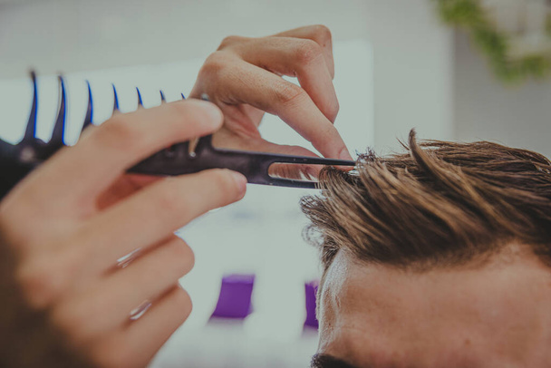 деталь молодого чоловіка з татуйованими руками вирізає волосся чоловіка в перукарні
 - Фото, зображення