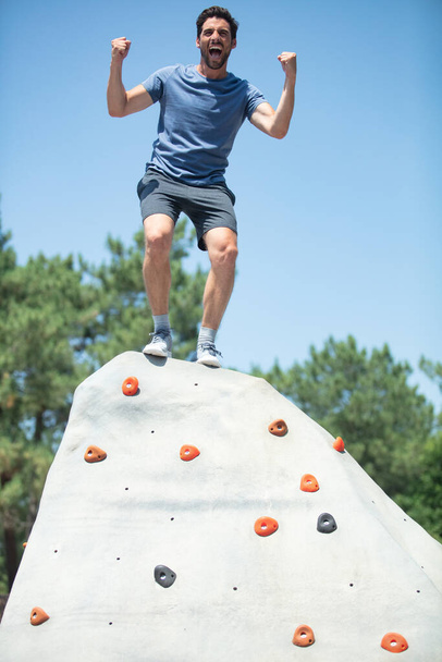 young man on top of climbing wall celebrate - Foto, immagini