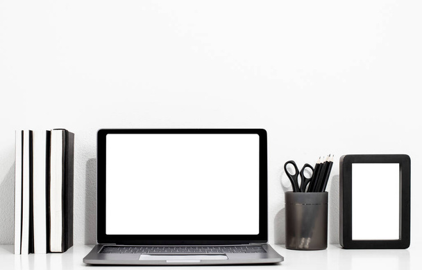 Digitální technika Laptop s prázdnou obrazovkou a knihou, rámeček na bílém dřevěném stole, interiér domu nebo kancelářské zázemí - Fotografie, Obrázek