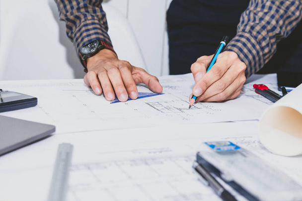 Konzeptarchitekten, Ingenieure mit Bleistift in der Hand zeichnen Planskizzen auf dem Schreibtisch mit einer Blaupause im Büro. .Selektiver Fokus - Foto, Bild