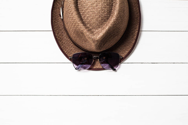 Masanın beyaz tahtasına kahverengi şapka ve güneş gözlüğü, mesajınız için alanı kopyalayın. - Fotoğraf, Görsel