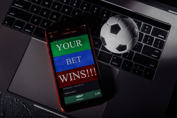 キーボード上のギャンブルモバイルアプリケーションやサッカーボールとスマートフォン。スポーツと賭けの概念 - 写真・画像