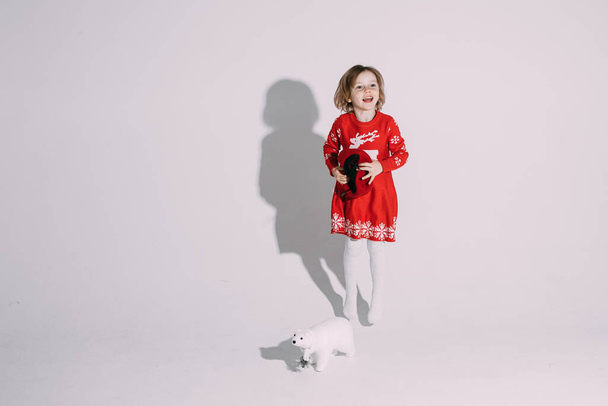 klein meisje in rode jurk houdt een hoed en lacht - Foto, afbeelding