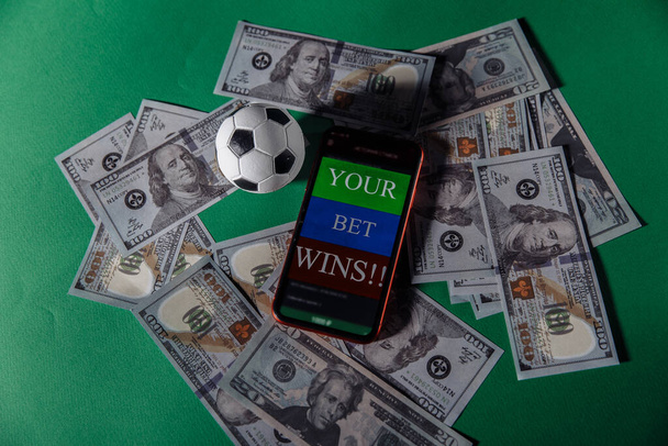Smartphone mit Glücksspiel-App und Fußball auf grünem Hintergrund - Foto, Bild