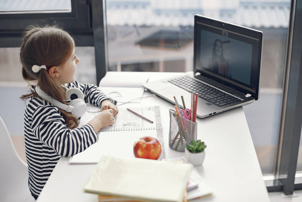 Little girl studying online using her laptop at home - Foto, Imagen