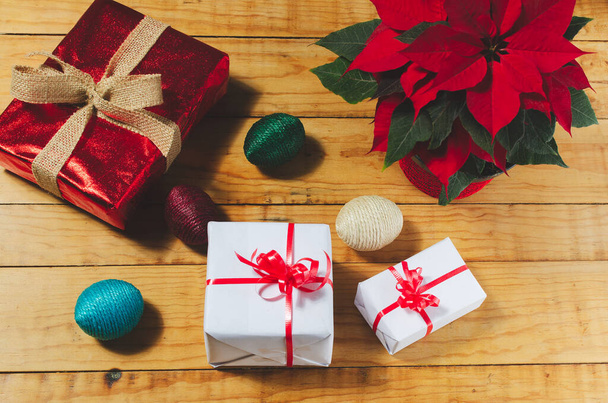 Fa asztal karácsonyi ajándékokkal és poinsettia növény - Fotó, kép