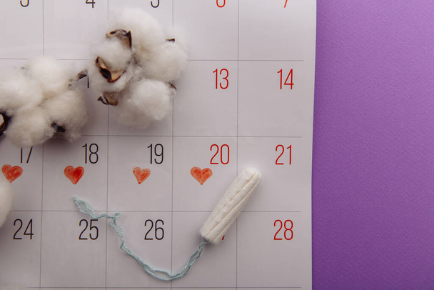 Tampão de algodão e calendário em um fundo lilás. Proteção de higiene para dias críticos da mulher - Foto, Imagem
