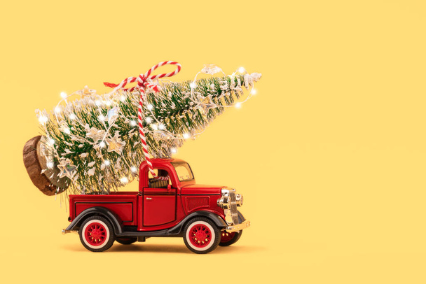 Красный маленький ретро-игрушечный грузовик с искрящимися елочными огнями на кузове грузовика на золотом фоне. Доставка, распродажа, новогодняя концепция. Копирование пространства, селективная фокусировка. - Фото, изображение