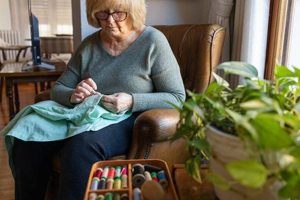 Mujer vieja cosiendo en casa - Foto, imagen