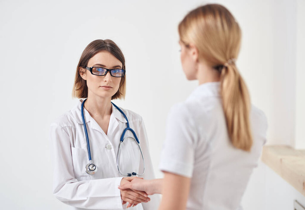 orvos orvosi köpenyben sztetoszkóppal és egy fehér pólós beteg visszapillantással - Fotó, kép