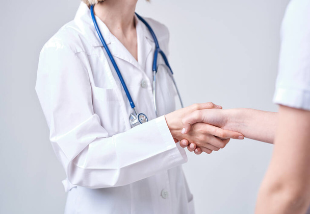 Professional doctor woman shakes hand of a female patient on a light background - Foto, Bild