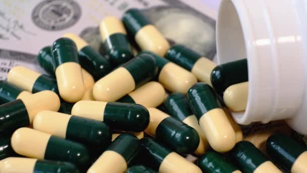 Αμερικάνικα δολάρια χαρτονομίσματα και πολλά ιατρικά χάπια σε κίτρινες πράσινες κάψουλες σε ένα περιστρεφόμενο τραπέζι. Πληρώστε χρήματα για τη θεραπεία, φάρμακα, βιταμίνες, φάρμακα. - Πλάνα, βίντεο