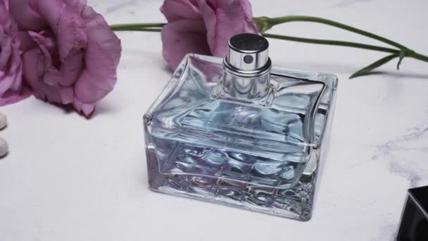 Butelka perfum i piękne kwiaty na jasnym tle - Materiał filmowy, wideo