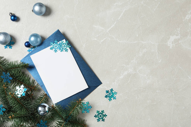Επίπεδη σύνθεση με λευκή ευχετήρια κάρτα και χριστουγεννιάτικη διακόσμηση σε γκρι μαρμάρινο τραπέζι, χώρος για κείμενο - Φωτογραφία, εικόνα
