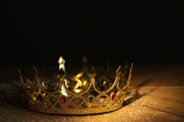 Beautiful golden crown with gems on wooden table. Fantasy item - Foto, Imagen