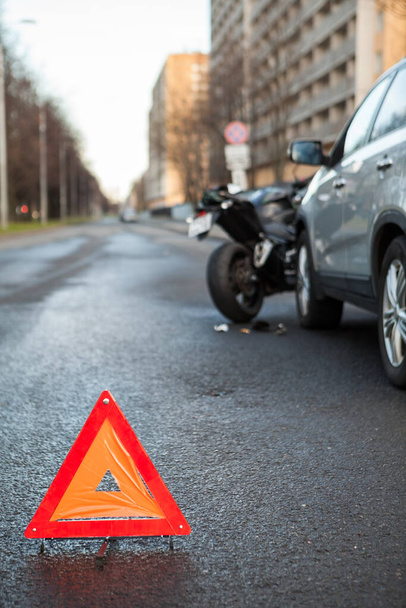 Triangular safety reflector is on asphalt road, sign is on the distance of car and motorcycle crash, nobody - Valokuva, kuva