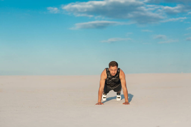 Fitness man doing exercises in sand desert. Sport concept. - Fotó, kép