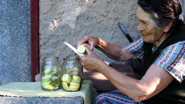 Vanhukset nainen siivu raaka squash ja laittaa purkkiin - Valokuva, kuva