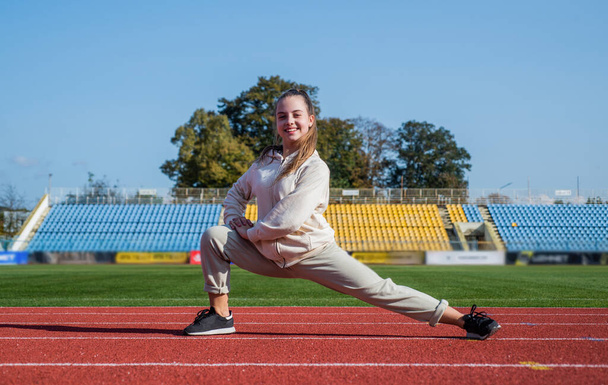 runner prepare for race competition. sprinter warming up on stadium gym. flexibility. child training at school physical education lesson. teenage girl stretching before run. Staying fit and healthy - Фото, изображение