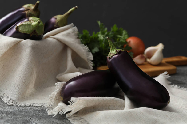 Ripe purple eggplants and napkin on grey table - Φωτογραφία, εικόνα
