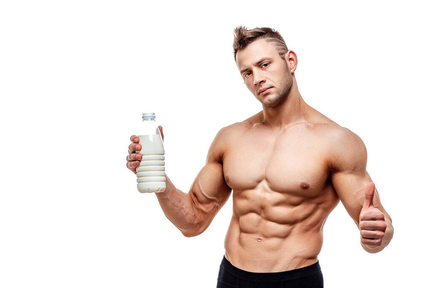 a bottle of milk in his hand, a man with sporty body posing on a white background - Fotó, kép