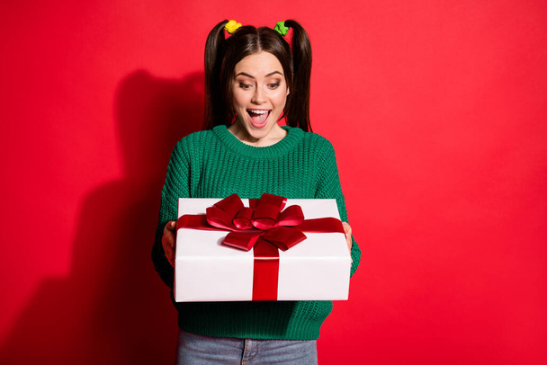 Photo of young beautiful shocked surprised smiling female receive gift present isolated on red color background - Foto, Imagem