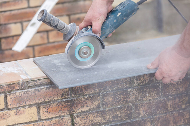 tiler cutting a tile with a grinder - Fotó, kép
