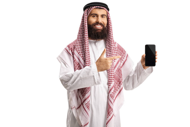 Arab man holding a smartphone and pointing isolated on white background - Foto, afbeelding