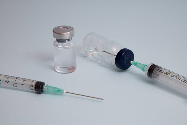 COVID вакцина, доза різниці вакцин Коронавірусу і розмір за допомогою голки, підготовка до ін'єкції, медична вакцина на блюзовому фоні. - Фото, зображення