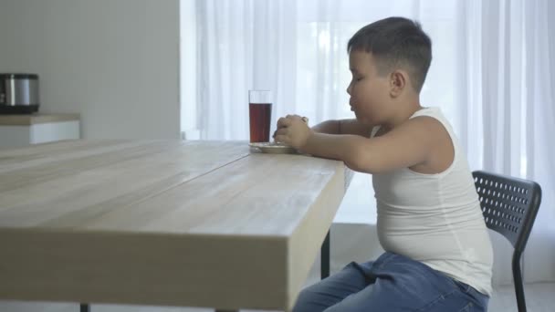 Übergewichtiger asiatischer Junge isst ungesunden Burger und trinkt zu Hause Cola - Filmmaterial, Video