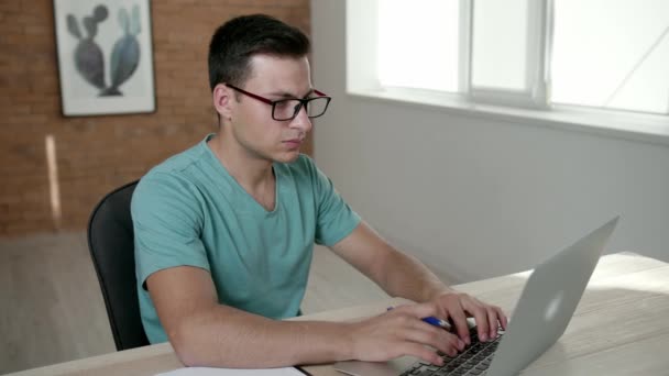 Молодий чоловік працює на ноутбуці в офісі
 - Кадри, відео