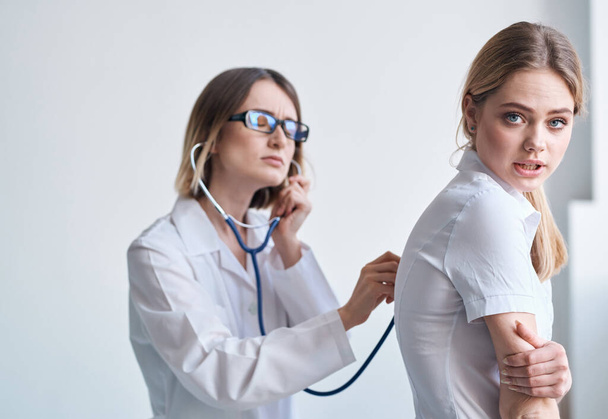 Professional doctor woman with stethoscope and female patient side view - Fotoğraf, Görsel