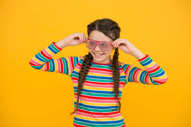 cheerful teenage girl. pretty kid with braided brunette hair. glamour and funny. beauty and fashion. child wear party glasses. happy childhood. just having fun. express positive emotions - Foto, afbeelding