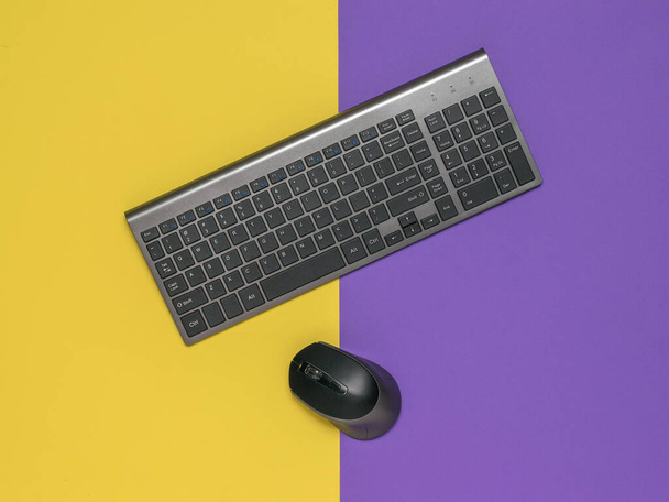 Stylish wireless keyboard and mouse on a yellow and purple background. - Fotografie, Obrázek