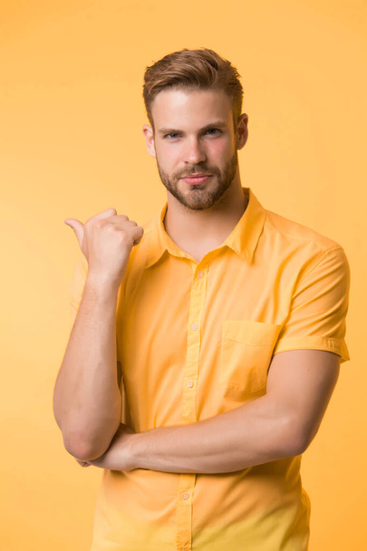 Solution is here. Handsome young man keeping hand on chin while stand yellow background. Hard question. Moral question difficulties. Listen to yourself. Question without answer. Pointing with finger - Fotografie, Obrázek