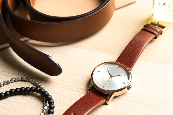 Luxury wrist watch, belt and bracelets on wooden background, closeup - Zdjęcie, obraz