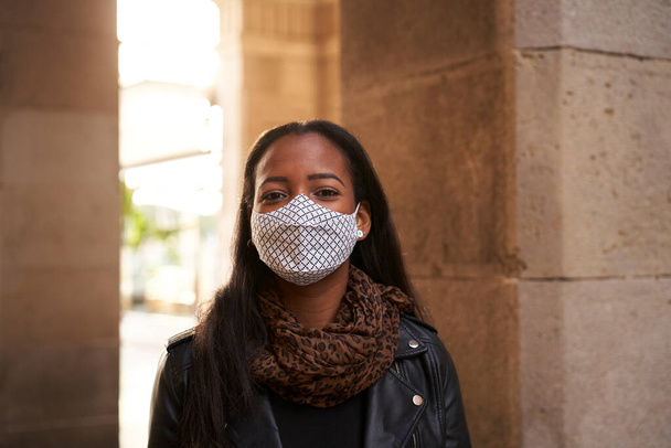 Dışarıdaki kameraya bakan yüz maskesi takan Afro-Amerikalı bir kadının portresi. Covid19 salgınından dolayı koronavirüs zamanlarında yeni bir normal.. - Fotoğraf, Görsel