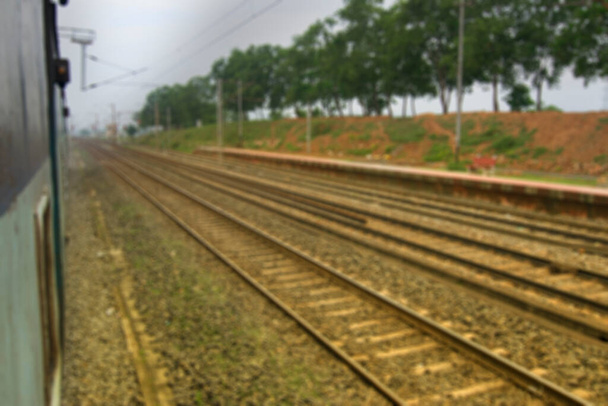Розмите зображення індійських залізничних ліній з зеленими деревами збоку.. - Фото, зображення