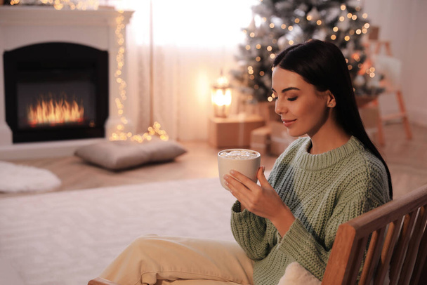 Young woman with cup of hot drink at home, space for text. Christmas celebration - Foto, Bild