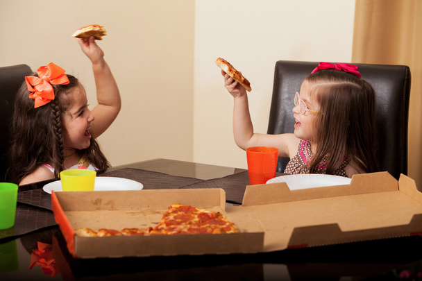 Bonitos primos divirtiéndose y haciendo un brindis con pizza en casa
 - Foto, imagen