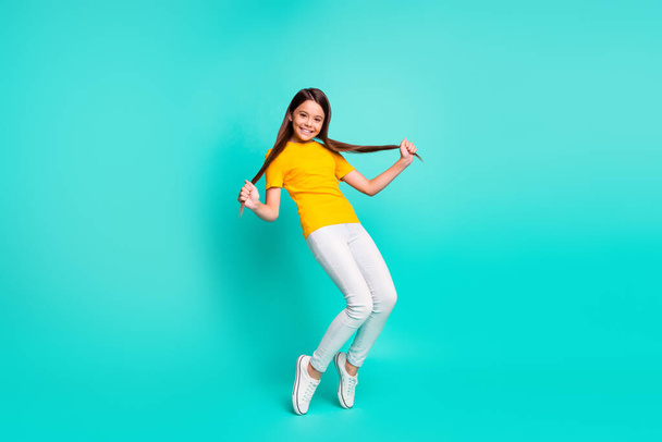 Full body photo of positive kid girl hold her haircut dancing isolated over teal color background - Photo, image
