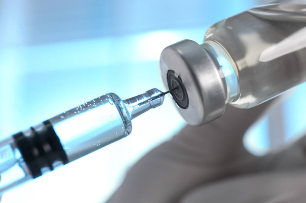 Doctor filling syringe with vaccine from vial on blurred background, closeup - Фото, зображення