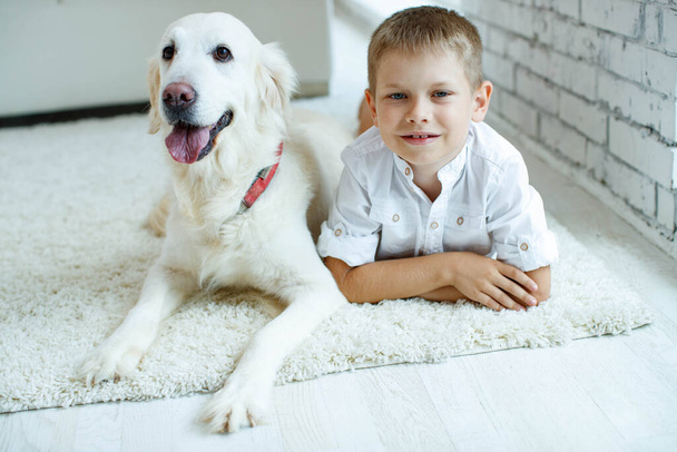 Little boy with a dog at home on the carpet. Friendship, care, happiness, new concept of the year. - Foto, imagen