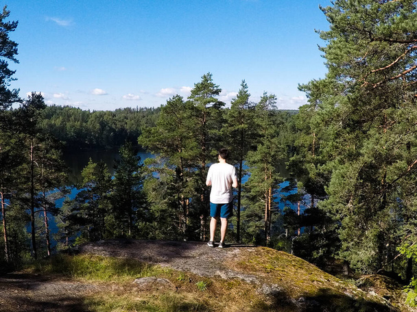 guy traveler looks at the lake in the forest - Valokuva, kuva