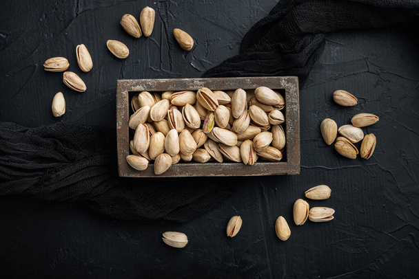Shelled, unsalted pistachios, on black textured background, flat lay - Foto, Imagen